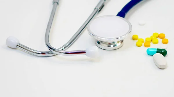 İlaçlar ve beyaz arka planda Doktor 'un kulaklıkları. Sağlık hizmeti kavramı. Ve yaşlılıkta tıbbi bakım..