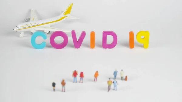 Minyatür bir kadın, minyatür bir adam, uçak ve Covid-19 konsepti ile seyahat ve enfeksiyon hakkında mektuplar..