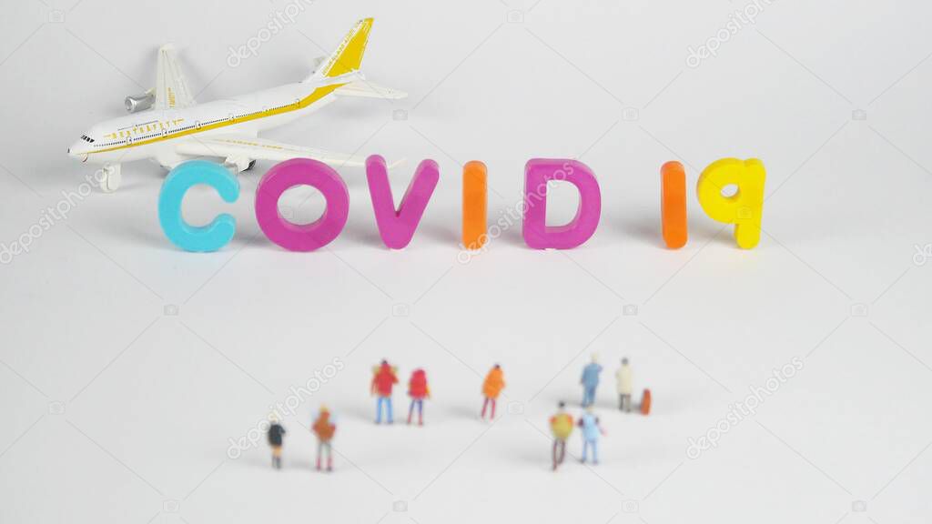 A miniature woman, a miniature man and aircraft and letters on white covid-19 in concept of travel and infection covid-19.