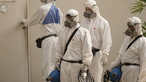 Bangkok / Tayland-21 Mart 2020: Koruyucu maskeli dezenfektan işçisi ve giysi bakteri veya virüs püskürtüyor. Covid-19 salgınlarını önlemek için ofis bölgesinde koronavirüs temizliği..