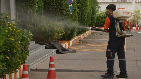 Bangkok / Tayland-21 Mart 2020: Koruyucu maskeli dezenfektan işçisi ve giysi bakteri veya virüs püskürtüyor. Covid-19 salgınlarını önlemek için ofis bölgesinde koronavirüs temizliği..