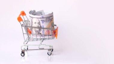 Süpermarketten gelen araba parayla dolu. Beyaz bir arka planda alışveriş arabasında dolar..