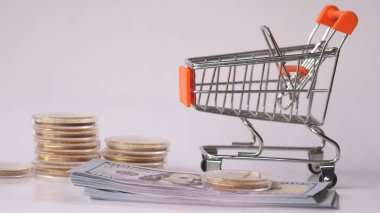 Süpermarketten gelen araba parayla dolu. Beyaz bir arka planda alışveriş arabasında dolar..