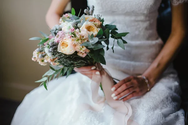 Bruid in jurk zittend op een stoel en houden bruiloft boeket van f — Stockfoto