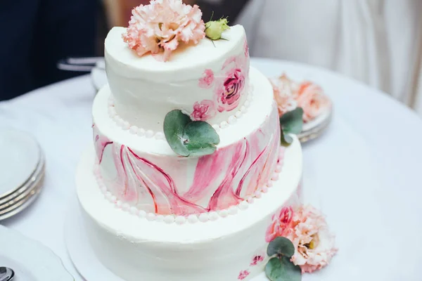 Sweet multilevel wedding cake on wedding banquet with pink rose