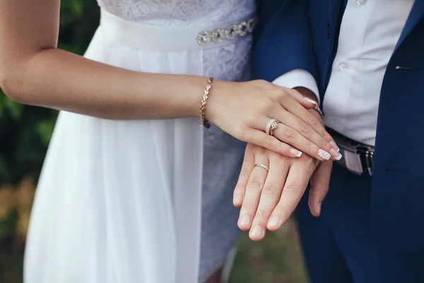 Vigselringar. Brudgummen i en kostym och bruden i en vit dres — Stockfoto