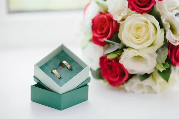 Anéis de casamento em caixa verde e buquê com rosas brancas e vermelhas — Fotografia de Stock