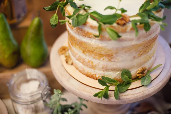 Белый свадебный торт украшен зеленью, стоит на столе в — стоковое фото