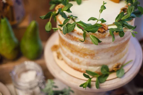 Белый свадебный торт украшен зеленью, стоит на столе в — стоковое фото