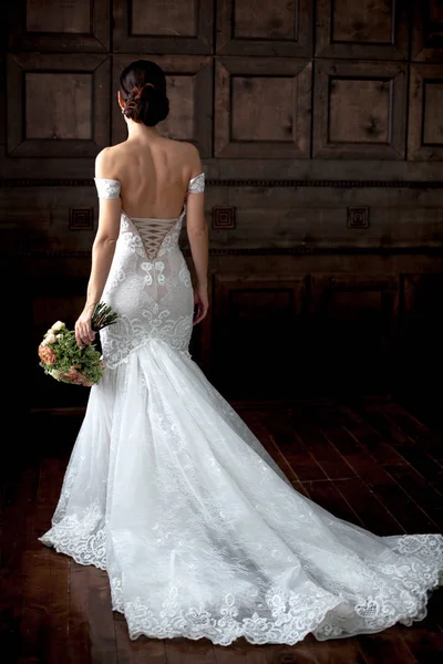 Eleganza sposa in abito sexy con schienale aperto tenendo bouquet in b — Foto Stock
