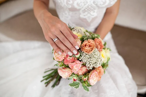 Mãos de noiva com manicure bege no buquê de casamento.Close-up — Fotografia de Stock