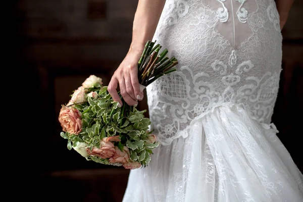 Mariage. Bouquet à la main de mariée, vue du dos. Mariée en robe blanche sexy sur fond sombre.espace de copie pour le texte — Photo