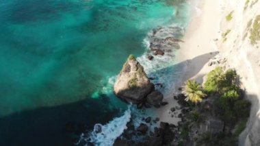 Tropik sahil manzarası, deniz taşları, turkuaz okyanus, palmiye ağaçları ve dalgalar. Atuh Sahili, Nusa Penida Adası, Bali, Endonezya. seyahat konsepti. İHA