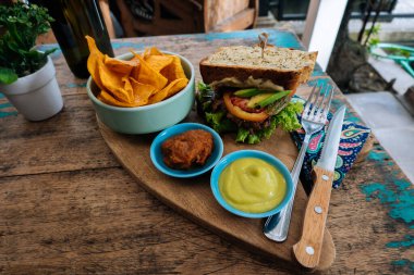 Fast food. Bir pirzola ile burger üst görünümü, tatlı patates kızartması ve iki sosile marul. Kafede ahşap masada öğle yemeği için lezzetli sandviç. sağlık gıda kavramı