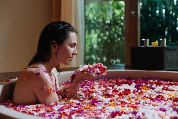 열 대의 꽃, 유기농 피부 관리, 호화 온천 호텔, 라이프 스타일 사진 이 있는 야외 목욕을 하면서 손 안에 있는 꽃향기를 즐기는 여성 — 스톡 사진