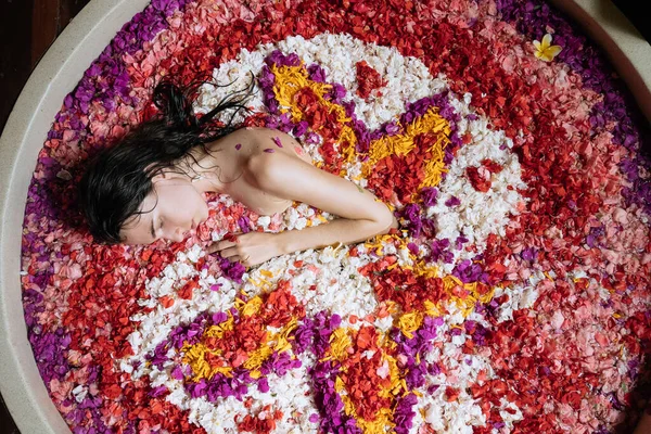 Vista superior de la mujer relajante en el baño grande redondo con flores tropicales. Increíble enorme baño en la jungla tropical.Organic cuidado de la piel en baño caliente en el balneario de lujo . —  Fotos de Stock