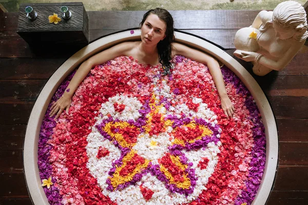 Belleza joven Mujer relajante en baño al aire libre con flores tropicales.Spa, concepto de cuidado orgánico y de la piel . — Foto de Stock