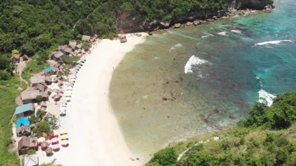 Piękna plaża zatoka z turkusową wodą oceanu z wieloma parasolami widok z góry zdjęcie lotnicze z białą plażą i dżunglą tropikalnej wyspy — Wideo stockowe