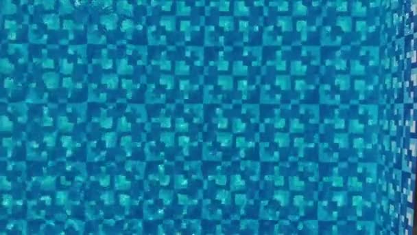 Aerial- blue swimming pool water with top view under the sunlight with ripple on water surface and blue mosaic tile background on summer holiday. — ストック動画
