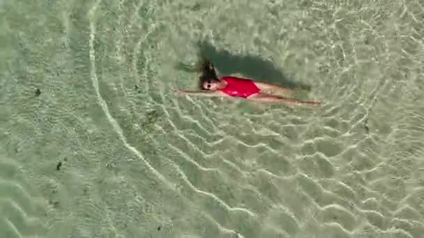 Directement au-dessus de la vue de dessus de la femme sourire heureux en bikini rouge et lunettes de soleil nageant dans l'eau cristalline claire dans l'océan profiter des bains de soleil pendant les vacances d'été. Concept tropique de voyage — Video