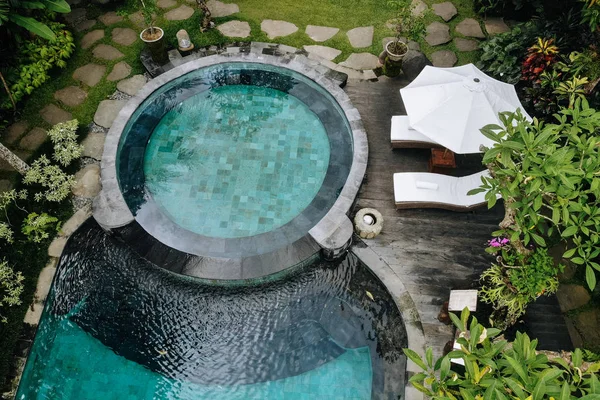 Вид с воздуха на роскошный круглый бассейн с белыми зонтиками и шезлонгами в тропических джунглях и пальмах. Шикарная вилла, бассейн в лесу, Убуд, Бали — стоковое фото