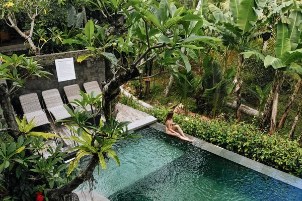 Vista posterior de la mujer en bikini en una piscina privada en Bali admira una hermosa vista de las palmeras.Vacaciones de lujo.Niña descansando en la isla de Bali. Copiar espacio. Concepto de vacaciones —  Fotos de Stock