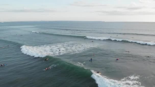 Canggu, Bali, Indonezja - luty 15 2019: Widok z lotu drona latającego nad linią w oceanie z surferami na deskach surfingowych fala połowów w Canggu znajduje się w zachodniej części Bali na zachód słońca z pięknym niebem — Wideo stockowe