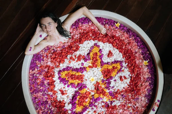 Mujer relajante en baño al aire libre redonda con flores tropicales, cuidado de la piel orgánica, hotel spa de lujo, foto estilo de vida, vista superior —  Fotos de Stock