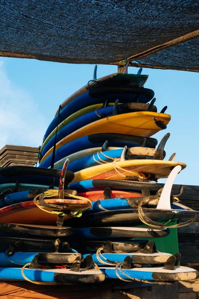 Set of different color surf boards in a stack by ocean.Bali.Indonesia. Surf boards on sandy beach for rent. Surf lessons on Weligama beach, Sri Lanka.