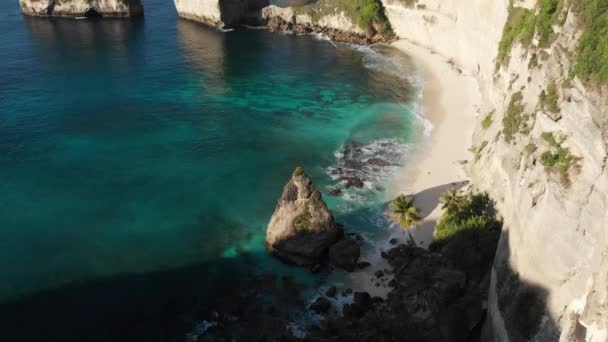 Topputsikt över tropisk strand, klippor, turkosa hav och palmer. Stranden Atuh, ön Nusa Penida, Bali, Indonesien. resekoncept. Drönare — Stockvideo