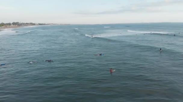 Canggu, Bali, Indonésie - Únor 15 2019: Letecký pohled na řadu v oceánu se surfaři na surfařských prknech chytání vlny v Canggu se nachází na západě Bali při západu slunce — Stock video