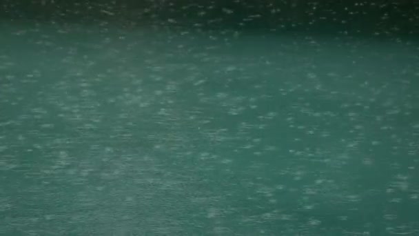 Tropický letní déšť cákající do bazénu. Zblízka bazén během bouře a kapky deště padající do vody. — Stock video