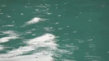 Tropik yaz yağmuru yüzme havuzuna sıçrıyor. Fırtına sırasında yüzme havuzunu kapatın ve yağmur damlaları suya düşsün..