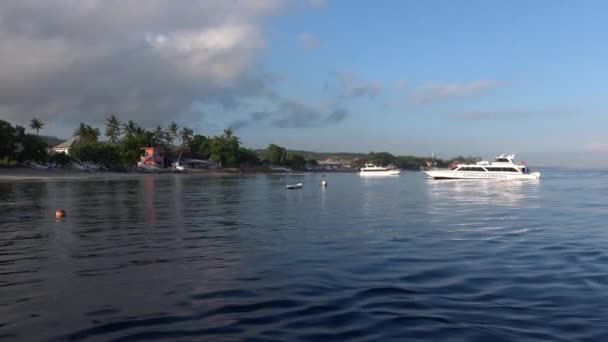 Barco a motor branco com turistas que se deslocam em direção à costa da ilha tropical em Nusa Penida de Bali, Indonésia, em dia ensolarado com céu azul e mar . — Vídeo de Stock