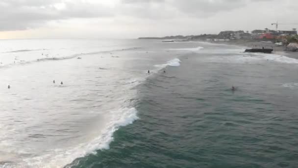 Canggu, Bali, Indonésia - Fev 15 2019: Vista aérea de drones voando sobre a linha no oceano com surfistas em pranchas de surf apanhando onda em Canggu localizado no oeste de Bali no pôr do sol com belo céu — Vídeo de Stock