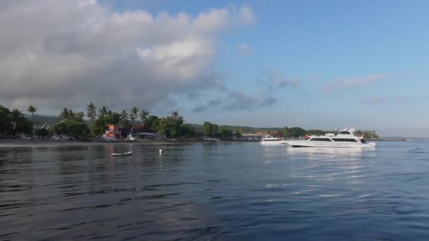 ヌサペニダ、インドネシア- 2019年2月15日:青い空と海と晴れた日にインドネシアのバリからヌサペニダの熱帯の島の海岸に向かって移動する観光客と白いモーターボート. — ストック動画