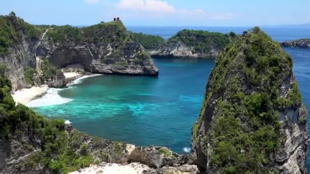 Lucht drone zoomen uitzicht op tropische strand, zee rotsen, turquoise oceaan en palmbomen. Strand van Atuh, Nusa Penida eiland, Bali, Indonesië. Tropische achtergrond en reisconcept — Stockvideo