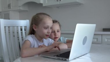 Avrupalı iki mutlu çocuk dizüstü bilgisayarda oturup evde ders çalışıyor, sosyal uzaklık, evde eğitim, covid-19 Coronavirus konsepti.