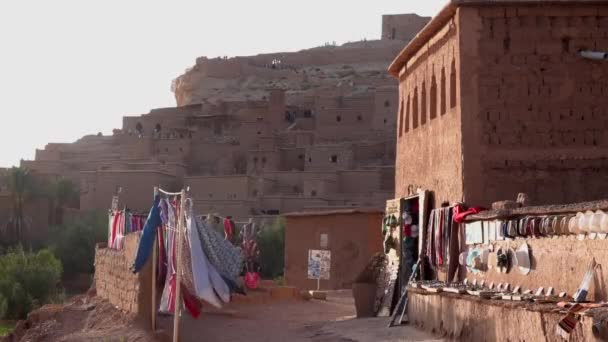 Straßenmarktstand in einem kleinen traditionellen marokkanischen Dorf ohne Menschen, Schals und Souvenirs, die auf beiden Seiten in Ait Benhaddou verkauft werden. — Stockvideo