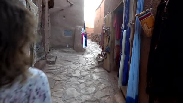 Neznámá žena kráčející prázdnou ulicí stánku na venkovním trhu v arabském starobylém městě Ait Benhaddou Maroko, zpomalený pohyb
