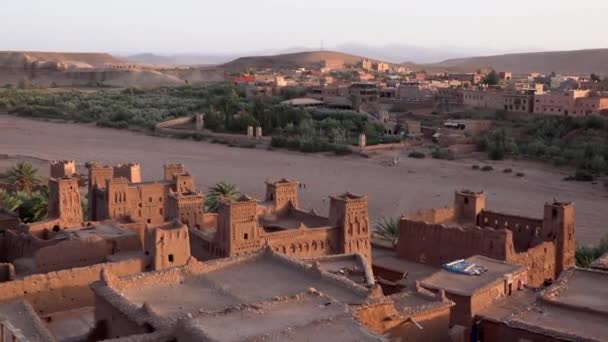 Vista aérea desde la cima de la antigua fortaleza ksar Ait Ben Haddou con casas de barro en el valle con vegetación, Marruecos cerca de Ouarzazate en las montañas del Atlas . — Vídeo de stock