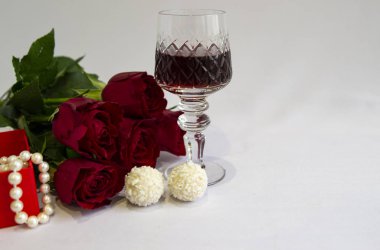 Red roses, pearl beads, glass of red wine, sweets - all on a white background, without anyone
