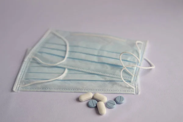 Tıbbi maske, beyaz arka planda beyaz ve mavi haplar. Kimse olmadan, beyaz bir arka planda. Enfeksiyondan korunma. COVID-2019 coronavirüsünden koruma.
