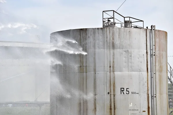 Bombero chorro de agua en el tanque de almacenamiento grande — Foto de Stock