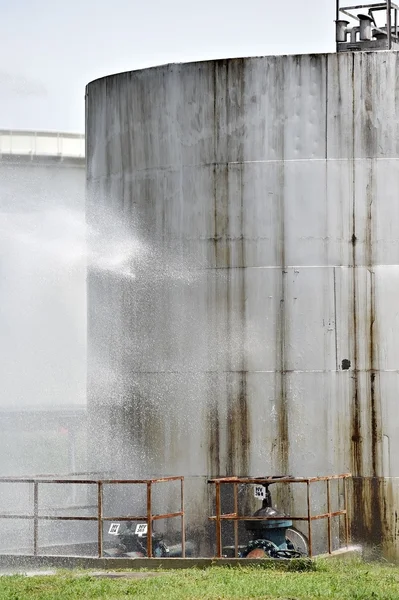 Bombero chorro de agua en el tanque de almacenamiento grande —  Fotos de Stock