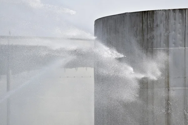 Firefighter water jet on big storage tank — Stock Photo, Image