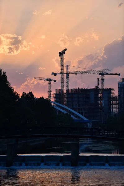 Construction cranes silhouetted at sunset — Stock Photo, Image