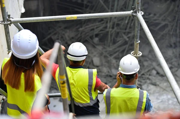 Workers inspecting construction works on a scaffold