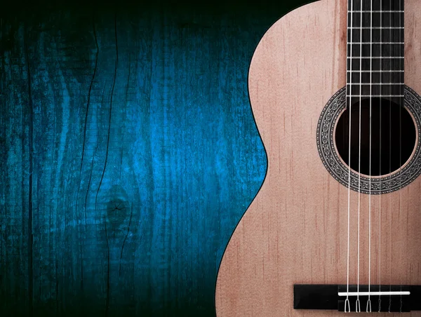 Ahşap arka plan üzerinde turuncu bir akustik gitar parçası.