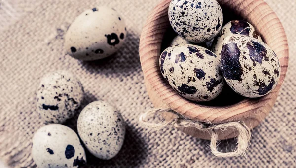 Huevos de codorniz crudos en un tazón de madera sobre fondo de arpillera — Foto de Stock